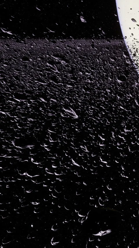 Raindrops glisten on a dark surface under soft light creating magic Stock Footage 341397937