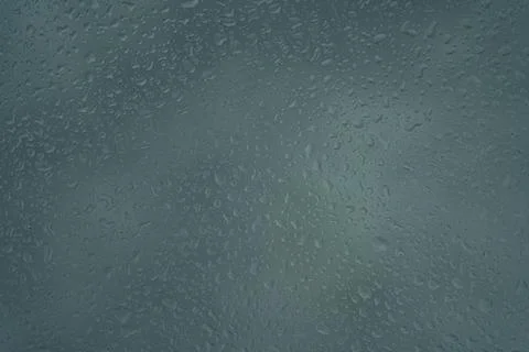Raindrops on a grey surface creating a textured and abstract pattern. Stock Photos