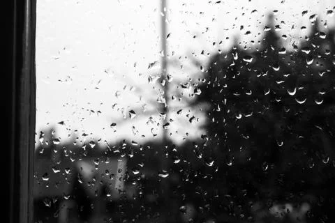 Raindrops on a old window with contrast by light sky and dark vegetation Stock Photos