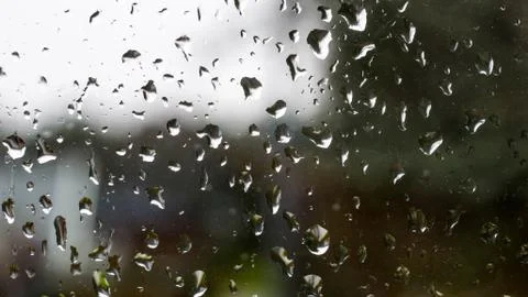 Raindrops on a old window with contrast by light sky and dark vegetation 스톡 사진