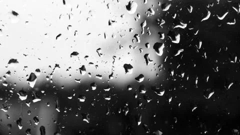 Raindrops on a old window with contrast by light sky and dark vegetation Foto stock