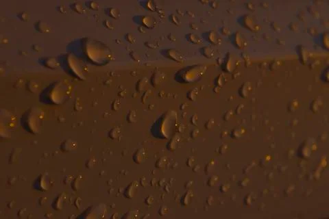 Raindrops or dew on a white plastic surface at sunset Stock Photos