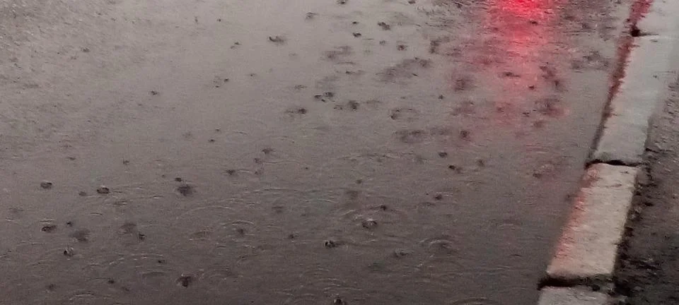 Raindrops on a puddle on the road Stock Photos