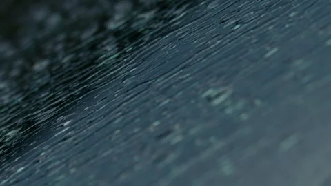 Raindrops resting on a dark surface create beautiful reflections in a serene Stock Footage 309333951