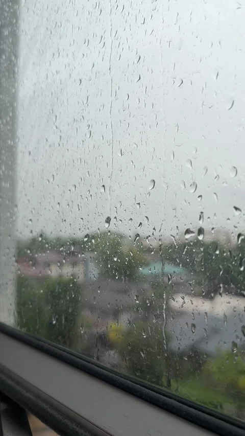 Raindrops resting on a window pane during a rainy day Stock Footage 339060179
