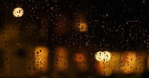 Raindrops rolling down on a window at night with blurred and defocused reside Stock Footage 125224894