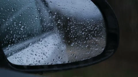 Raindrops run down the glass and mirror of the car Stock-Footage 168615541
