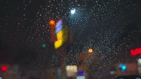 Raindrops run down the glass of the car against the backdrop of the bright Stock Footage 147519912