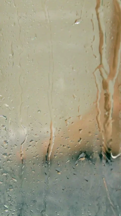 Raindrops run down glass window with blurry person behind Video stock 331992008
