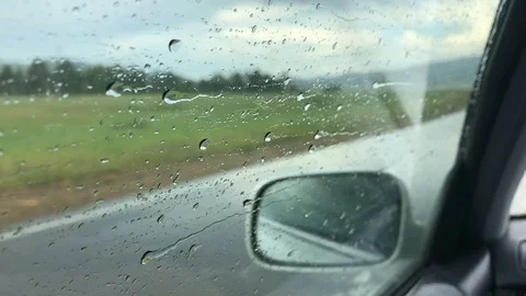 Raindrops run down the side window of the car while driving Stock Footage 124791586