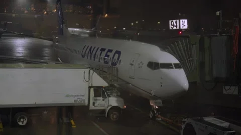 Raindrops run down a window with a United Airlines passenger jet in the back Stock Footage 241497990