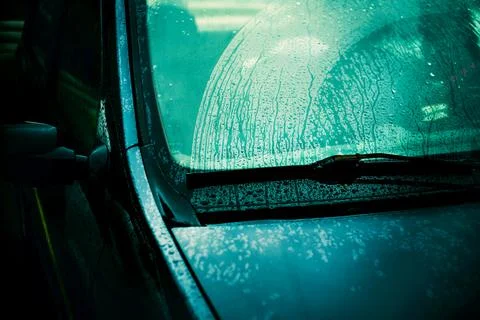 Raindrops run down the windshield of a passenger car, which are removed by th Stock Photos