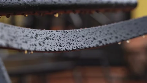 Raindrops running down the back of a black metal chair outside. The autumn Stock Footage 267755234