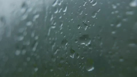 Raindrops running down clear glass illuminated by soft daylight forming 스톡 동영상 323077515