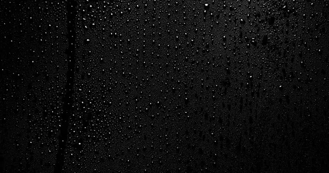 Raindrops running down on left side on black surface Stock Footage
