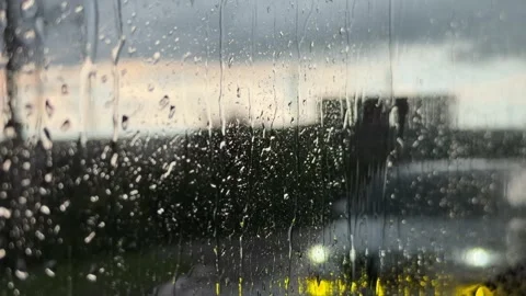 Raindrops slide across a vehicle window with a roadway and distant horizon visib Stock Footage 338001689