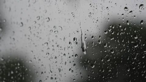 Raindrops sliding down a glass window pane on a rainy day Stock Footage 340833443