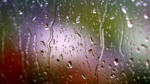 Raindrops sliding down window glass with colorful blurred background in slo.. Stock Footage 337519967
