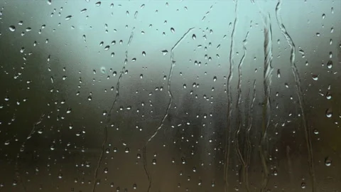 Raindrops sliding fast down a window pane with the background out of focus Stock Footage 226898356