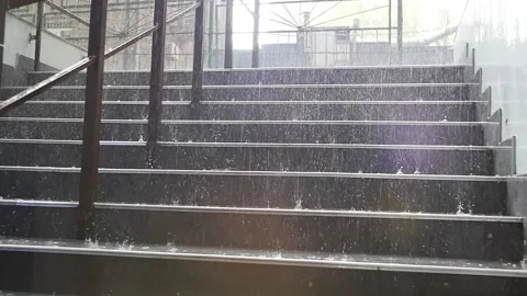 Raindrops in slow motion fall on the steps of the stairs creating splashes of wa Stock Footage 239709661