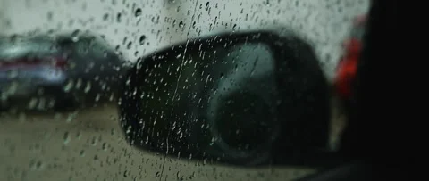 Raindrops speckle a car window and side mirror, creating blurred street ref.. Stock Footage 337022735