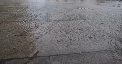 Raindrops splashing in puddles on pavement during torrential rainstorm Stock Footage 118993799