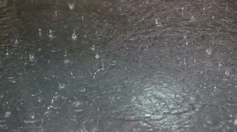 Raindrops splatter and form ringlets in the accumulated rainwater. Stock Footage 46513056