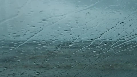 Raindrops streak down a window overlooking a stormy sea Stock Footage 318194193
