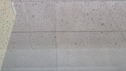 Raindrops streak glass, view down concrete patio Vidéo 339642059
