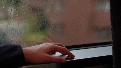 Raindrops on Train Window with Woman’s Hand in Frame Stockbeeldmateriaal 314534374