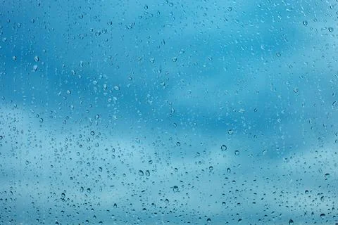 Raindrops on the transparent window pane. Background of raindrops. Stock Photos