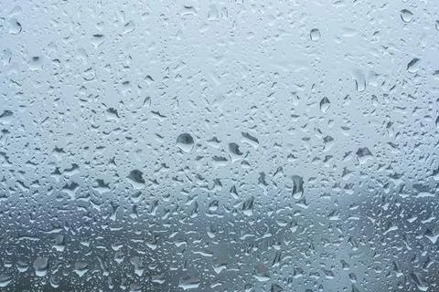 Raindrops on the transparent window pane in rainy weather. Stock Photos