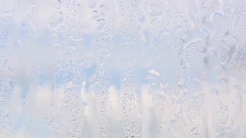 Raindrops trickle down the window glass against the blue sky on a clear day. Stock Footage 246499569