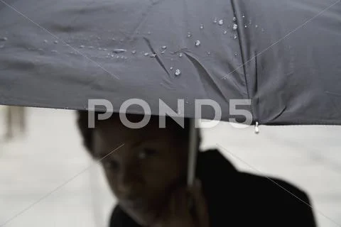 Raindrops on an umbrella with woman in background Stock Photos