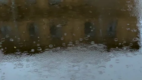 Raindrops on water surface with blurred reflection of building. Stock Footage 316683957