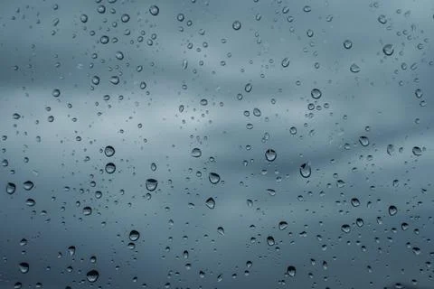 Raindrops on window against cloudy gray sky Stock Photos