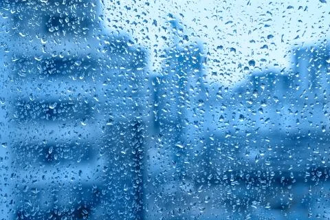 Raindrops on the window on a blue background Stock Photos