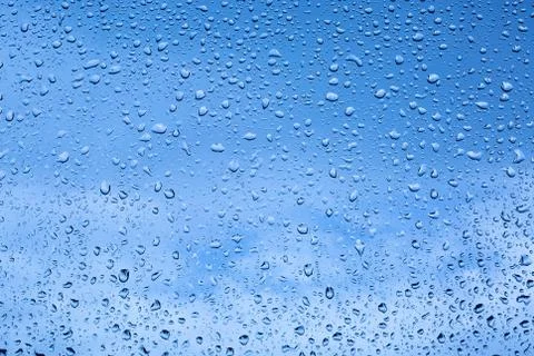 Raindrops on the window on a blue background Stock Photos