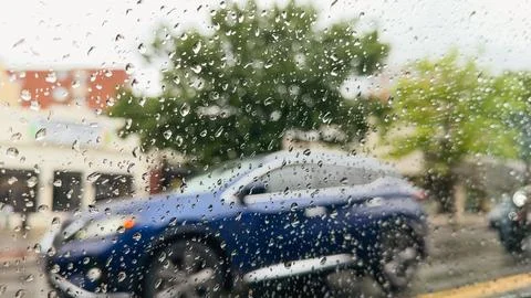Raindrops on window with blurred blue SUV outside Stock Photos