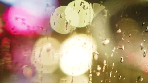 Raindrops on Window Blurring Pink and Yellow City Lights at Night Stockbeeldmateriaal 334852295