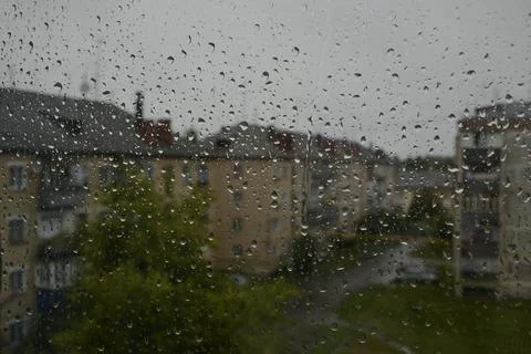 Raindrops on the window. Cloudy summer day and wet houses in the background Stock-Fotos
