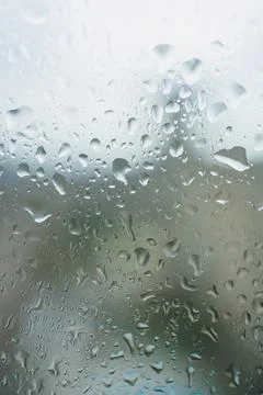 Raindrops on a window during a cloudy day in a city showing blurred buildin.. 스톡 사진