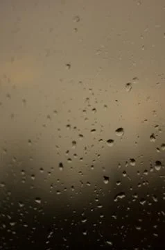 Raindrops on window glass on background of cloudy sky Stock Photos