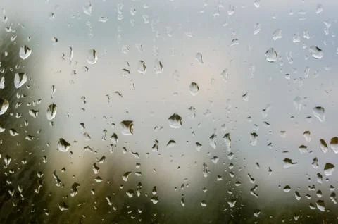 Raindrops on window glass on background of cloudy sky Stock Photos