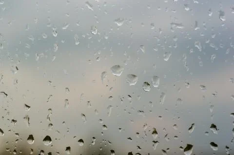 Raindrops on window glass on background of cloudy sky Stock Photos