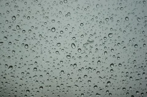 Raindrops on window glass on background of cloudy sky Stock Photos