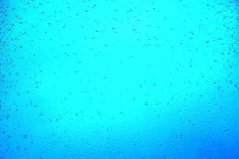 Raindrops on a window glass on a blurred blue background Stock Photos