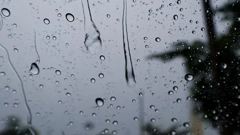 Raindrops on a Window Glass with Droplets Running Down Against a Gray Rainy Sky Stock Footage 344362904
