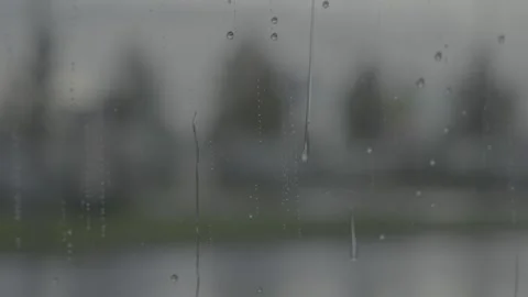 Raindrops on window glass surface and blurred street in the background Stock Footage 318415987