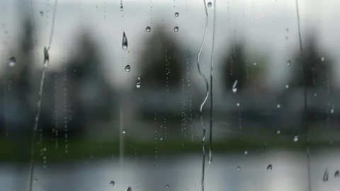 Raindrops on window glass surface and a blurred street in the background Stock Footage 318677640